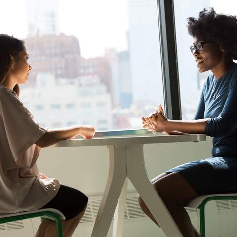 Zwei Geschäftsfrauen sitzen am Tisch und unterhalten sich